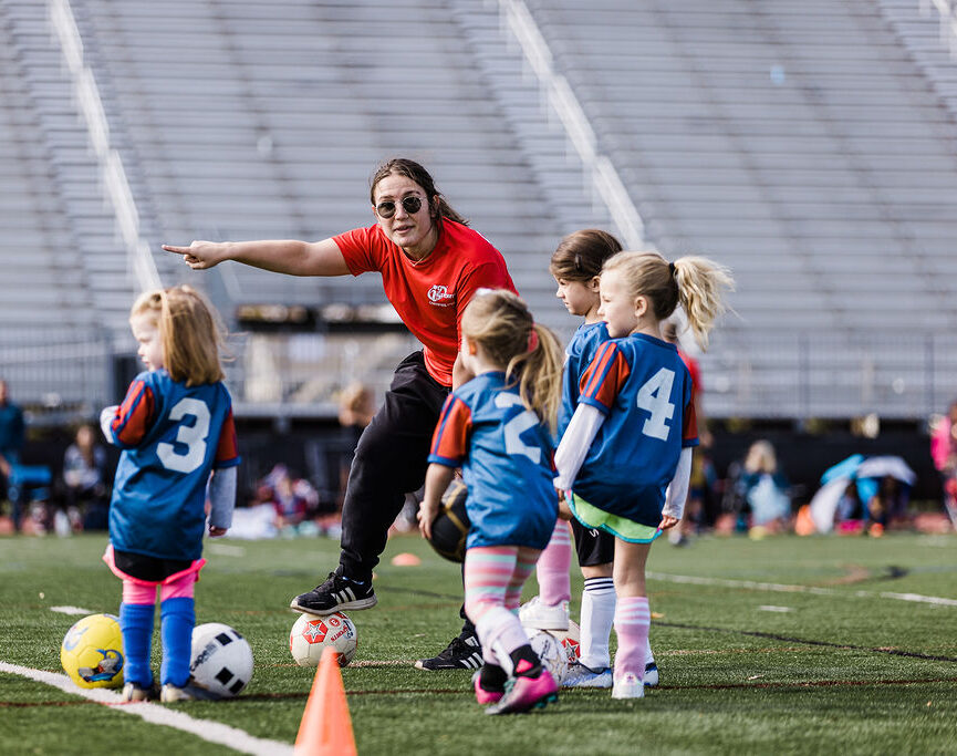 Coach pointing and telling young girl soccer player where to go on the field.