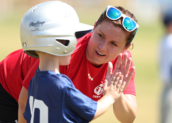 i9 Sports coach gives a high five to a kid playing t-ball