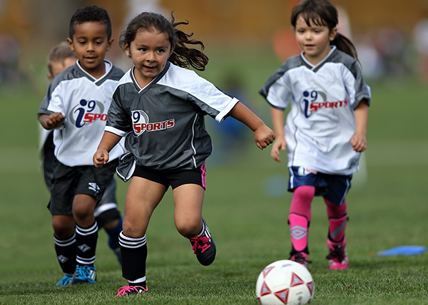 Female pee wee age group youth soccer player runs after the soccer ball during a game as three defenders chase after her