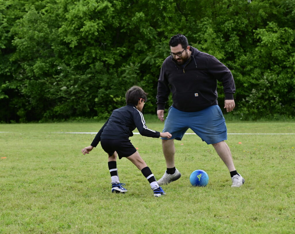 Father and son playing soccer before the son's youth soccer game.