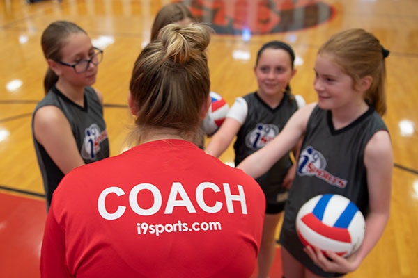 Youth volleyball coach encourages kids in the team huddle before the volleyball match